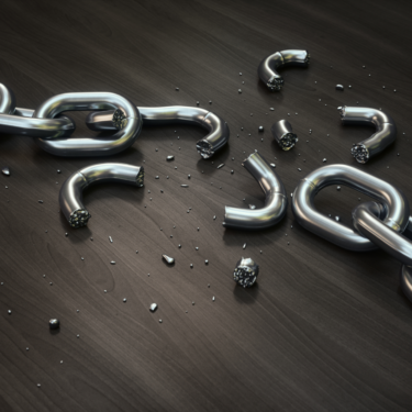 A broken silver chain scattered across a dark wooden surface, symbolising freedom from modern slavery