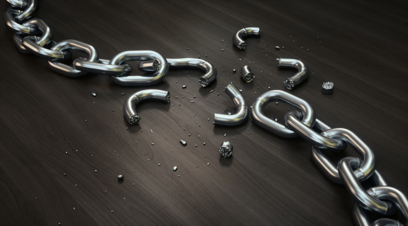 A broken silver chain scattered across a dark wooden surface, symbolising freedom from modern slavery