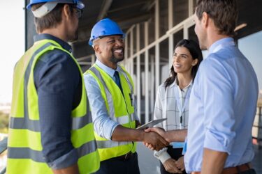 Smiling,Engineer,Shaking,Hands,At,Construction,Site,With,Happy,Architect.