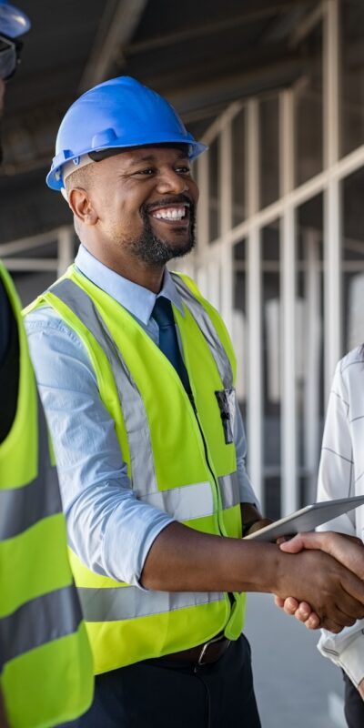 Smiling,Engineer,Shaking,Hands,At,Construction,Site,With,Happy,Architect.