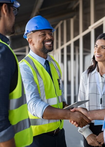 Smiling,Engineer,Shaking,Hands,At,Construction,Site,With,Happy,Architect.
